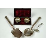 A cased pair of electroplate salt cellars, an electroplate sifting spoon and a pair of Indian