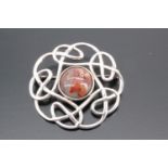 A Scottish white metal brooch, formed as a round hardstone cabochon set in a ring of Celtic