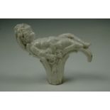 A white porcelain walking cane handle modelled as a putto slumbering atop a wheatsheaf and