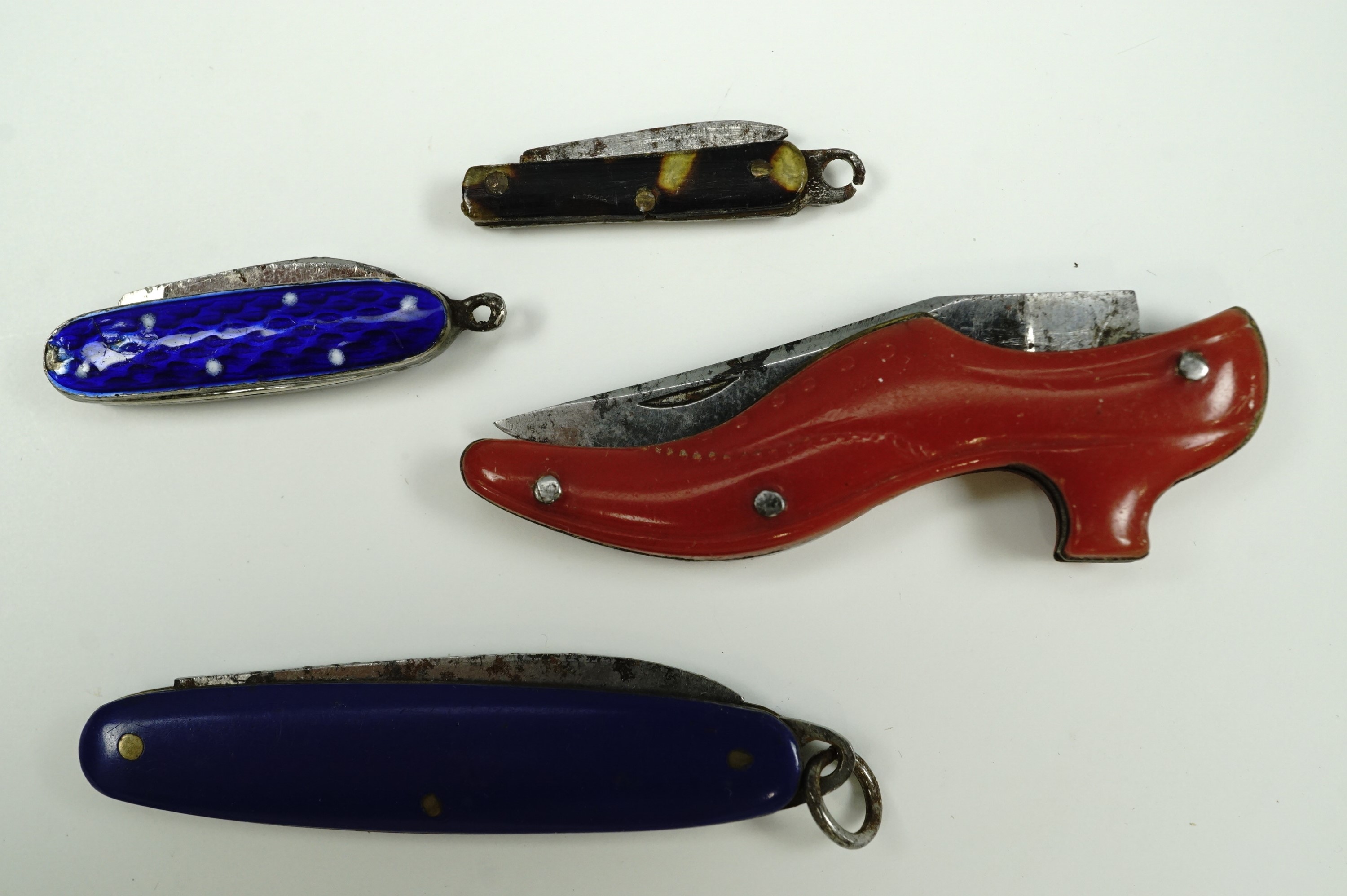 A novelty miniature penknife in the form of a lady's shoe with red plastic grip scales, 5 cm long