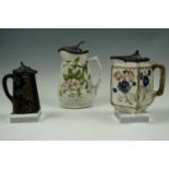 Three Victorian lidded jugs respectively decorated in depiction of apple blossom, majolica glazed
