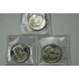Two 1964 John F Kennedy silver half dollar coins together with a silver Franklin half dollar