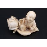 A Japanese ivory netsuke of a child sitting with a small animal, 4 cm