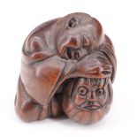 A Japanese carved wood netsuke of a man sleeping against a Daruma doll, 4 cm