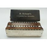 A cased Hohner "Chromatische" brass harmonica