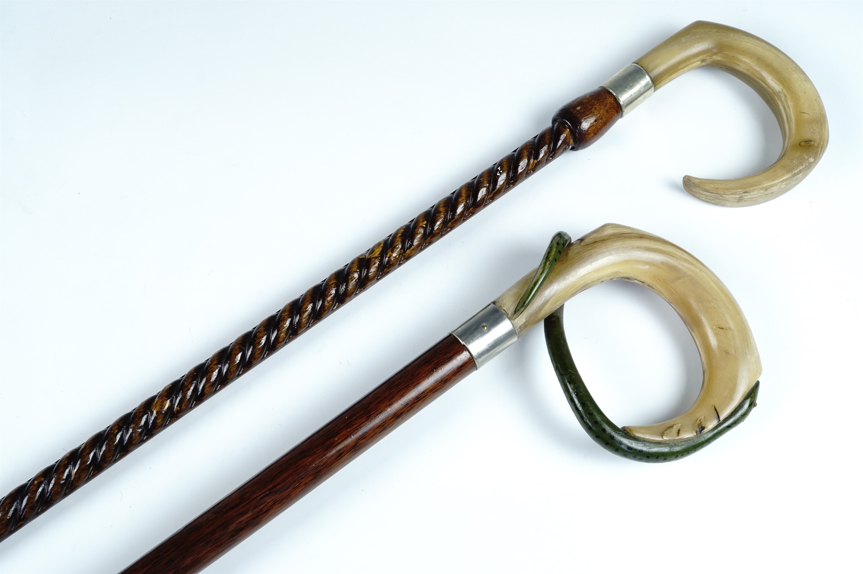 Two horn handled walking sticks, comprising a stick with a carved ram's horn handle on a reticulated