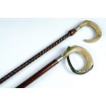 Two horn handled walking sticks, comprising a stick with a carved ram's horn handle on a reticulated