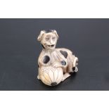 A Japanese ivory netsuke of a spotted dog perching on a ball and having a moving tongue, 4.5 cm