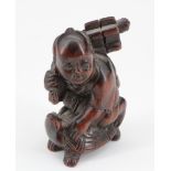 A Japanese carved wood netsuke of a schoolboy with books riding on a turtle, 5 cm