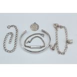 A selection of silver bracelets comprising a charm bracelet with two white metal charms, the padlock
