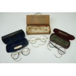 Four pairs of early 20th Century spectacles, gold filled, two in metal cases one pair in their
