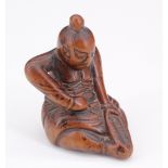 A Japanese carved wood netsuke of a seated Nio repairing a sandal, 4 cm