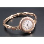 A lady's 9 ct gold wristwatch, on an expanding gold bracelet, the dial being engine turned, with