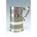 A late 19th / early 20th Century glass bottomed electroplate quart tankard decorated with banded