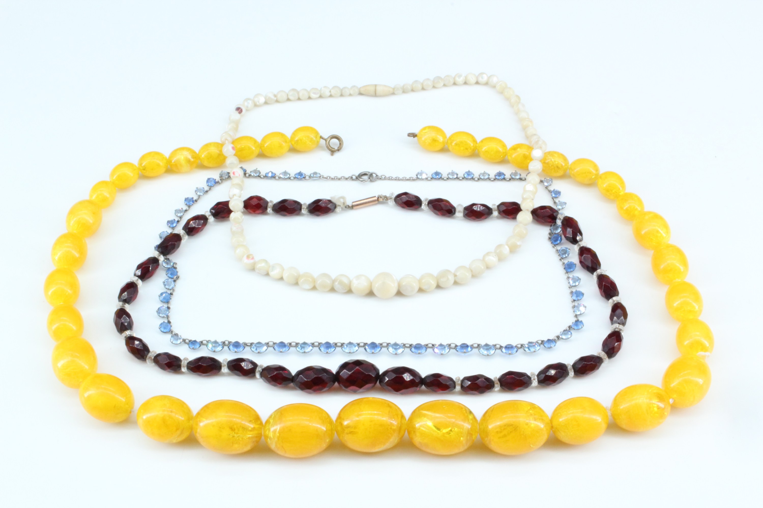 Two vintage faceted glass bead necklaces, a mother-of-pearl necklace and another of amber coloured