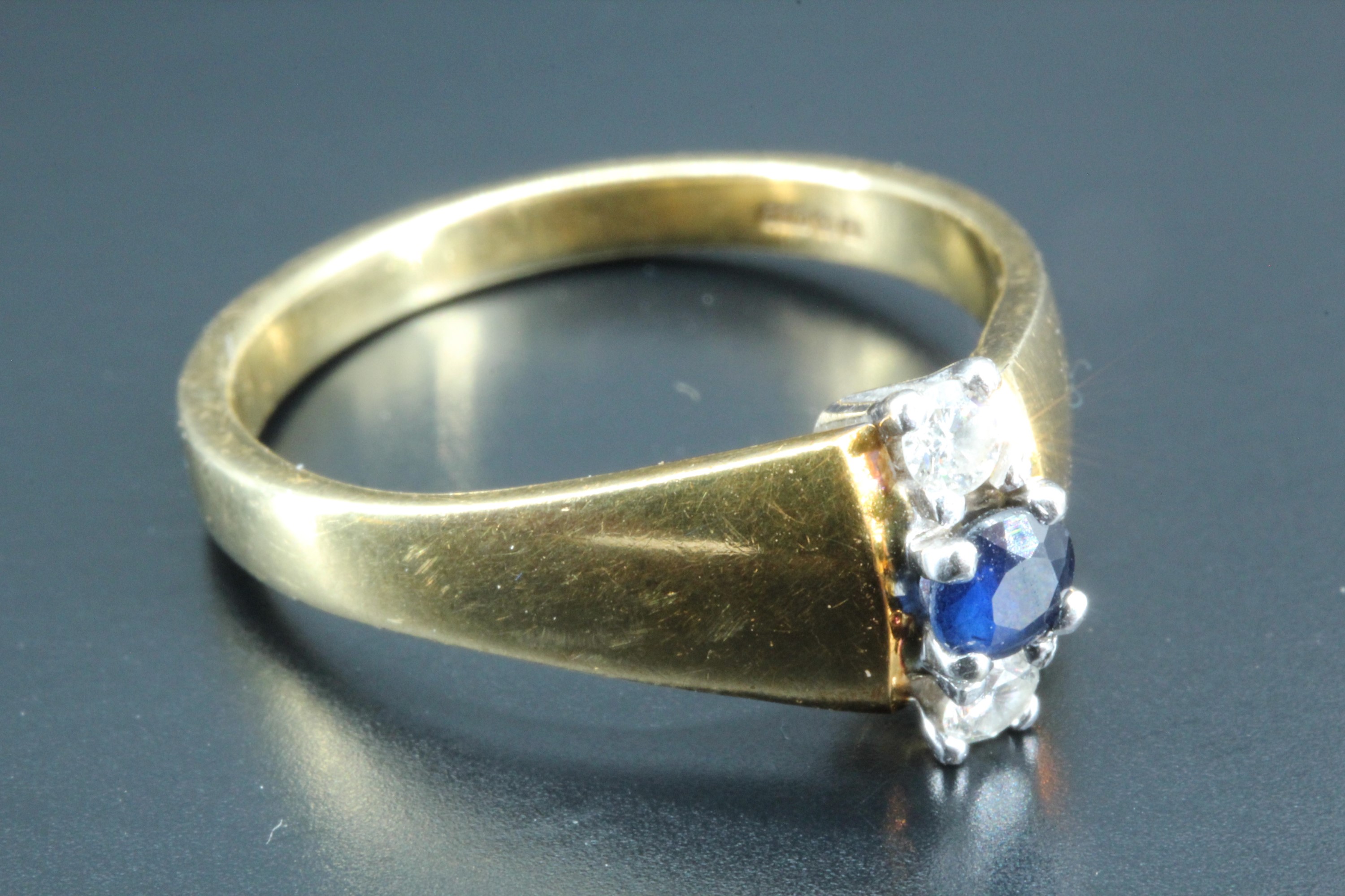 A contemporary diamond and sapphire ring, having a blue sapphire, approximately 0.1 carat, set