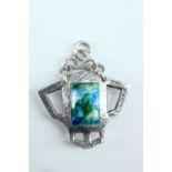 An Edwardian Arts and Crafts enamelled silver pendant, of geometric form, planished and centred by