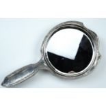 An early 20th Century silver hand mirror, of shield shape with a round bevelled mirror and having an