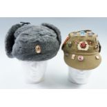 Two Cold War Soviet Bloc military caps, one bearing numerous badges