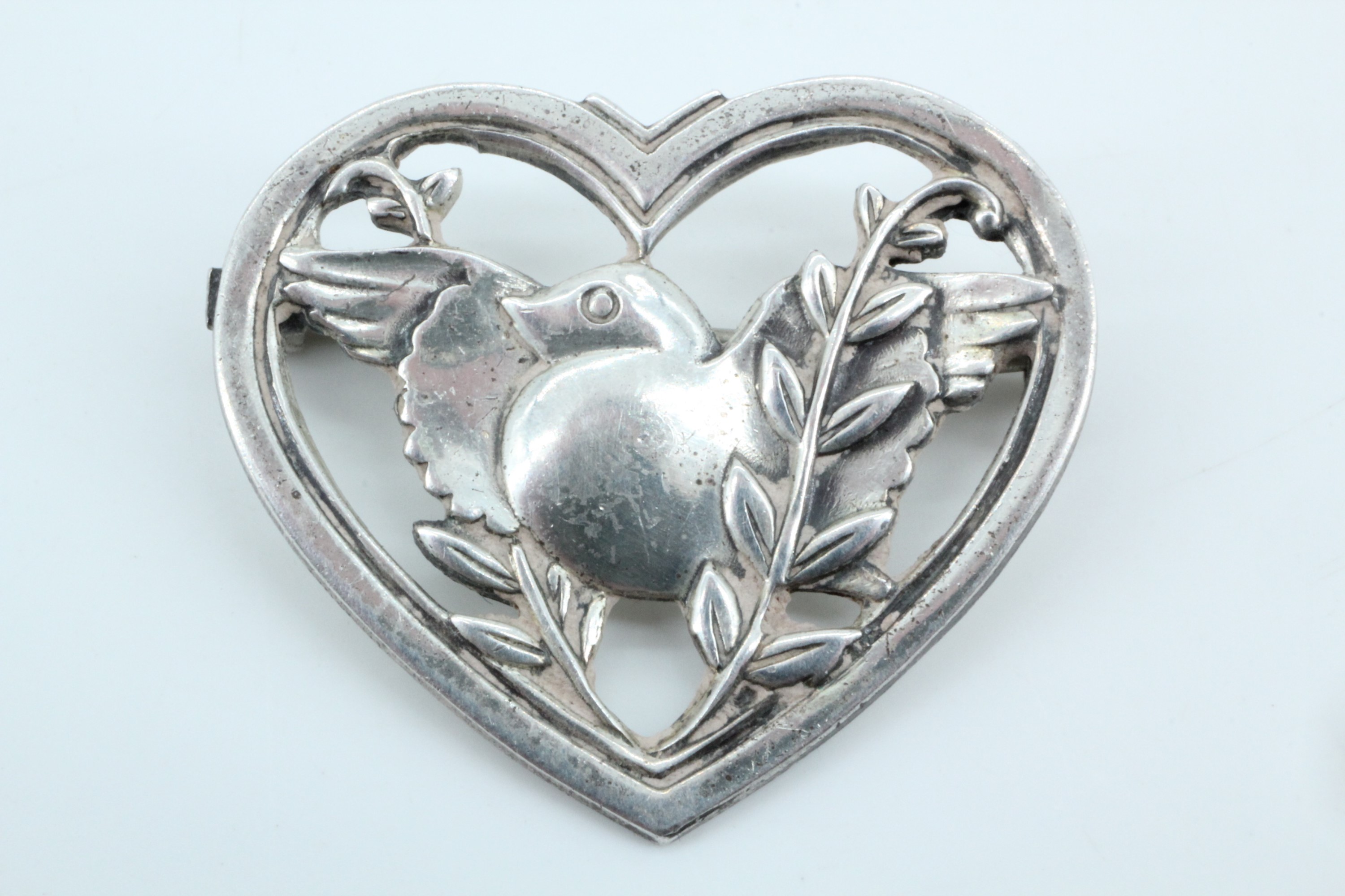 [George Jensen] Silver robin in a heart brooch by Coro, having a stylized robin in an openwork heart