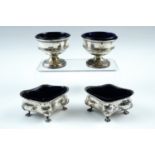 Two pairs of silver salt cellars with blue glass liners, being round bodied raised on a foot,