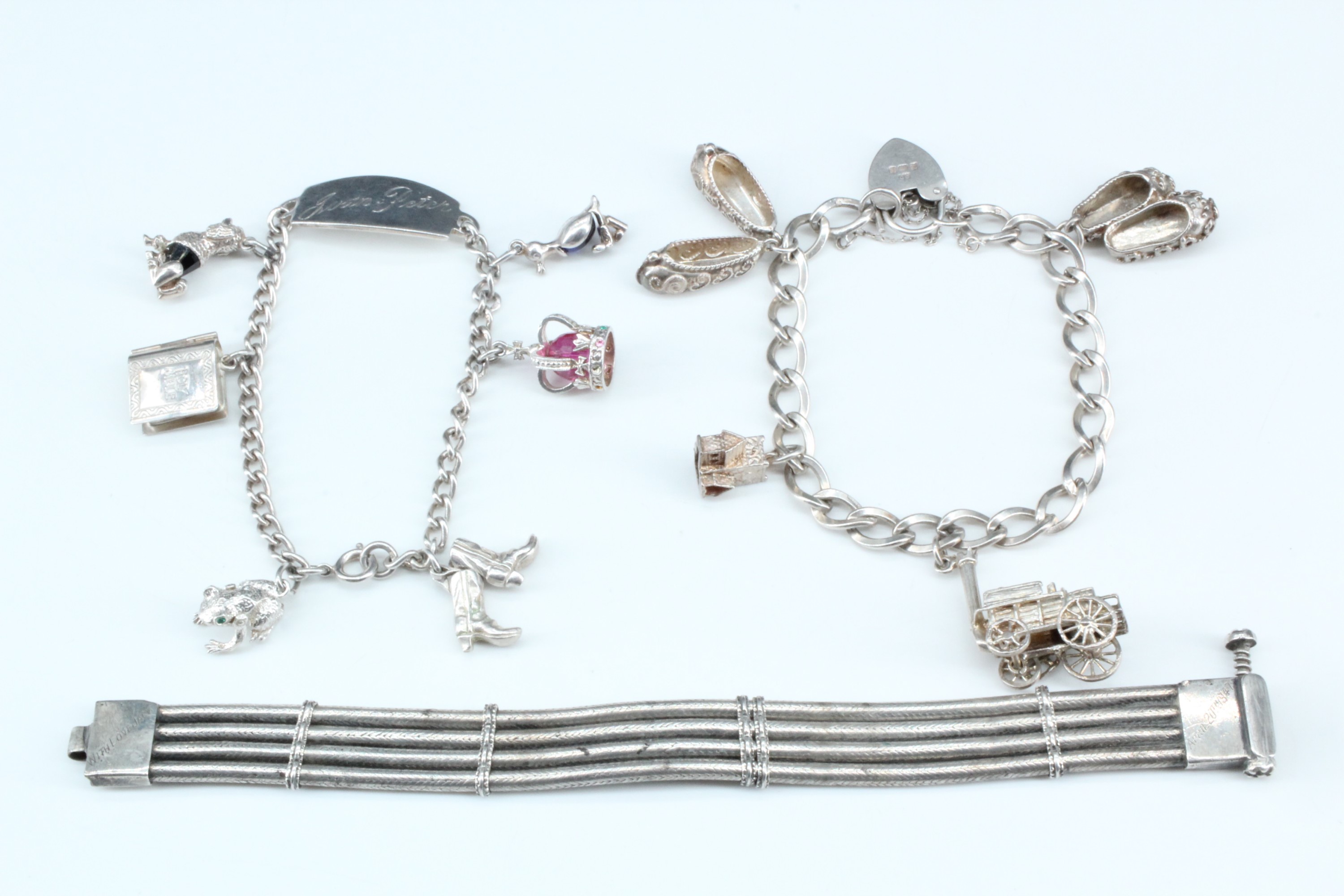 Two silver charm bracelets together with a 1940s quadruple snake link bracelet, 110 g