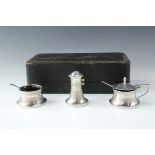 A cased Edwardian three piece capstan shaped condiment suite, comprising pepperette, salt cellar and