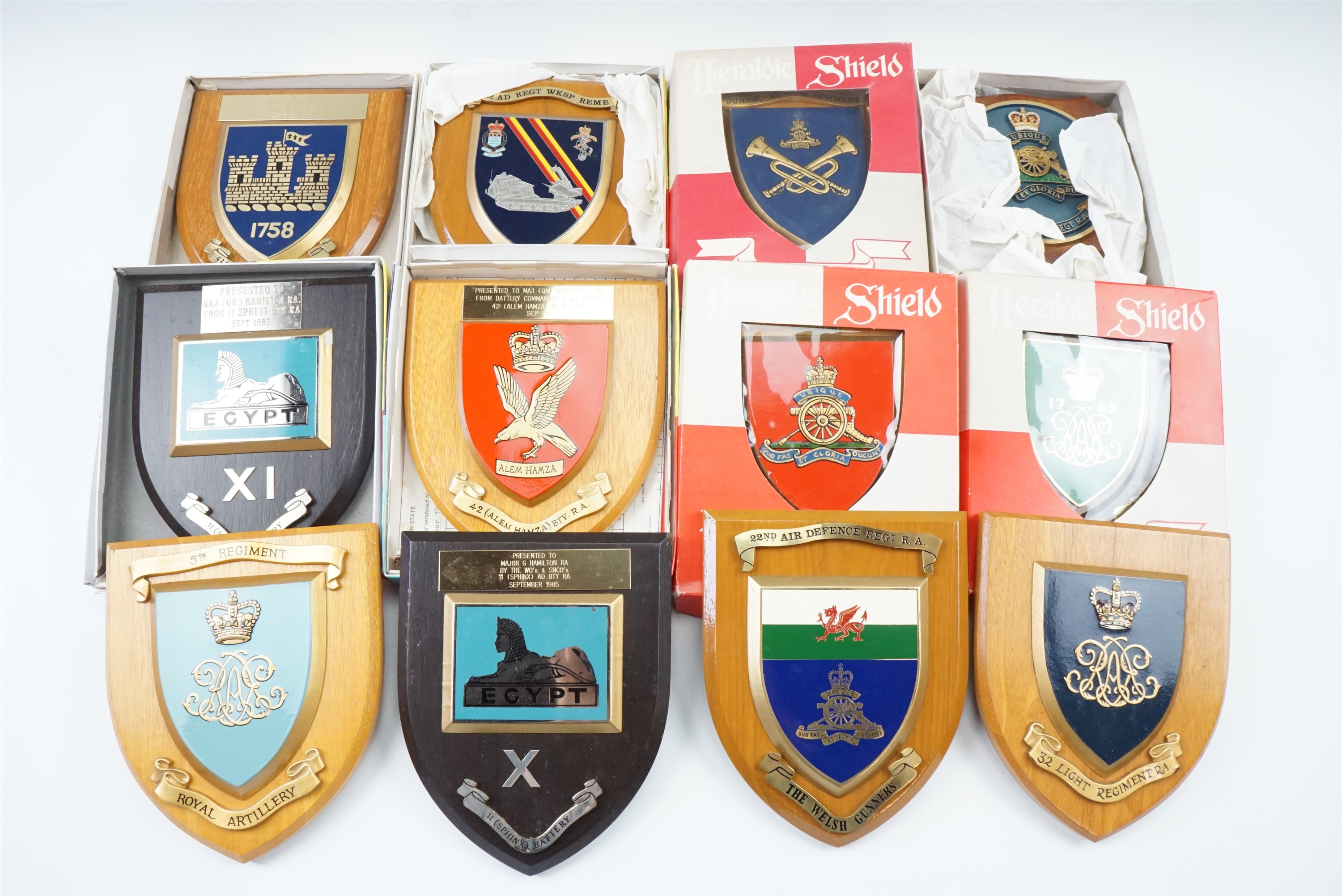 A quantity of military shield-shaped plaques, many in original cartons
