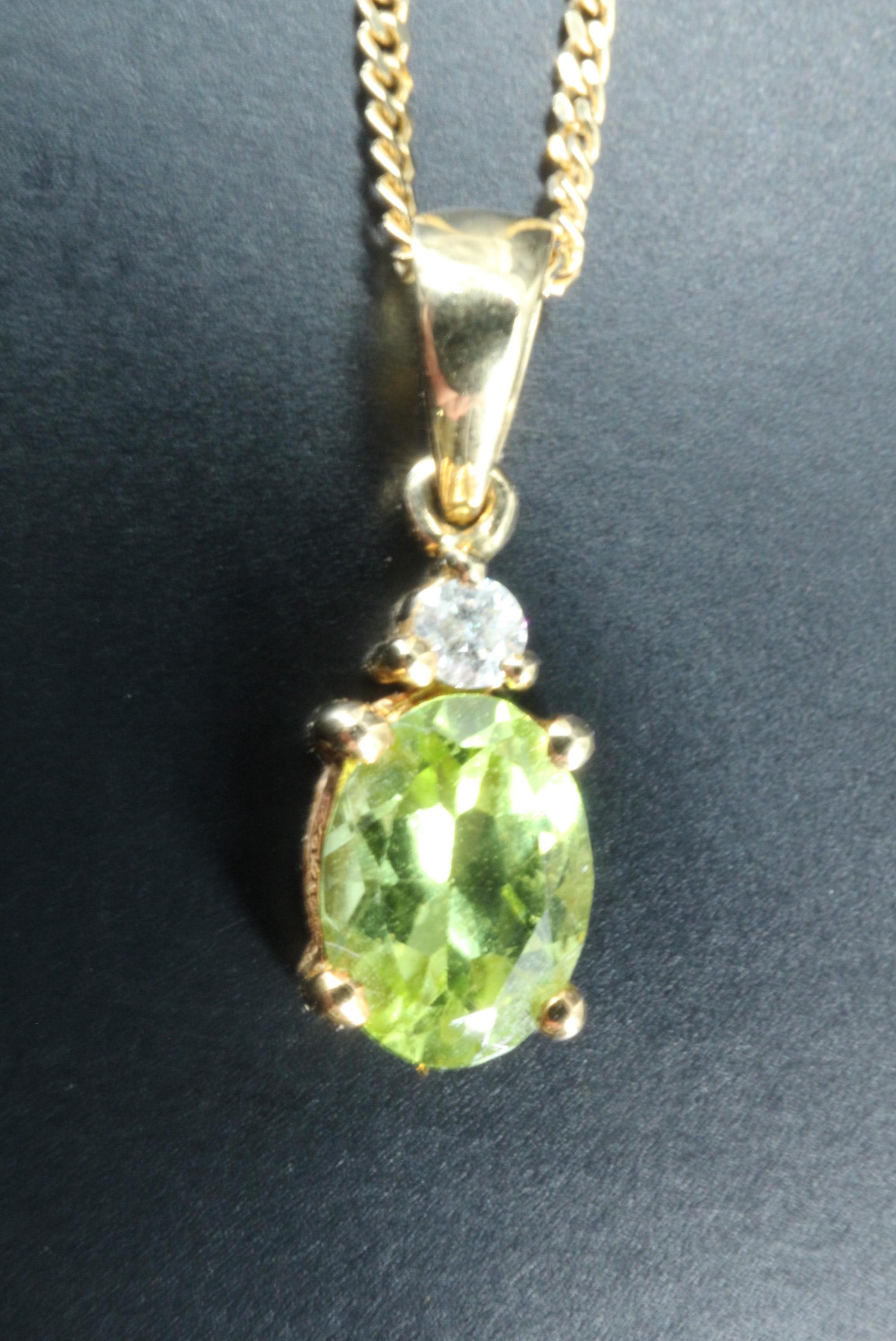 A peridot necklace, comprising an oval claw set peridot (8 x 6 mm) set below a small round