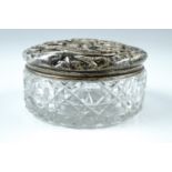 A silver-lidded cut glass dressing table tidy, the cover relief decorated in depiction of roses
