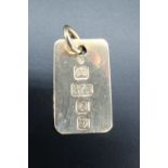 A 9 carat gold ingot pendant, formed as a thin gold sheet, the assay marks doubling as decoration,