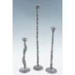 Patrick Meyer, (contemporary), Three slender pewter candlesticks, of organic spiral form, tallest 42