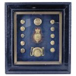 A framed display of Royal Household / Court livery insignia, including a buckle and saddlery