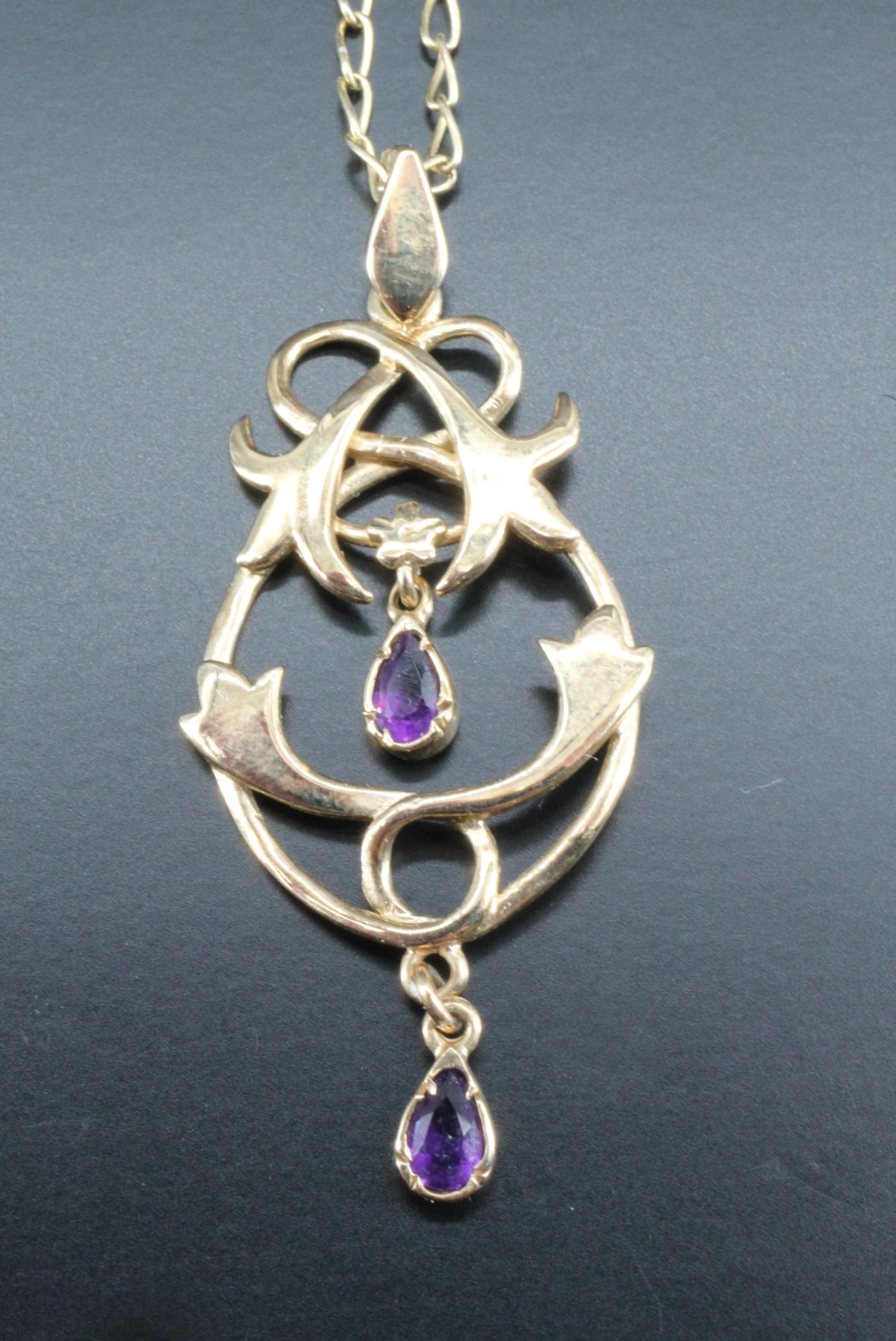 An amethyst set gold pendant, having floral scrolls suspending two pear shaped amethysts, 9 ct gold,