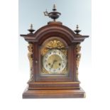 An Early 20th Century German walnut mantle clock, having a broken arch dial with Arabic numerals and