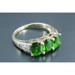 A lady's three stone dress ring, having three green oval stones approximately 4.5 x 7 mm, in a 9