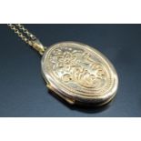 A 9 carat gold oval locket, having bright cut floral decoration to the front, hinged to reveal a