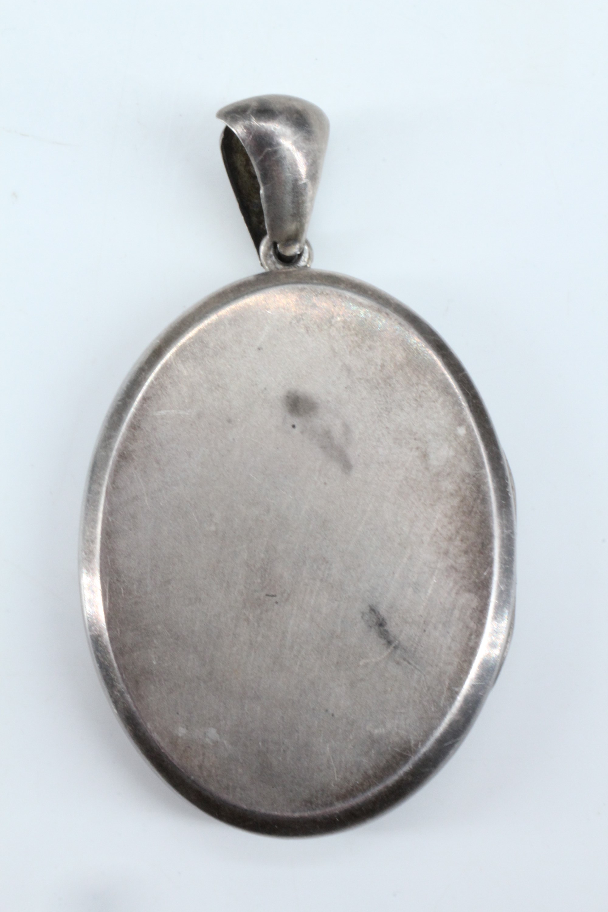 A Victorian Aesthetic Movement influenced white metal double pendant locket, its face shallow relief - Image 2 of 3