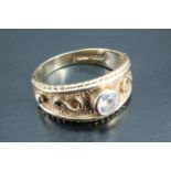 An unusual solitaire ring, being a 9 carat gold textured tapering broad band, with rope and bead