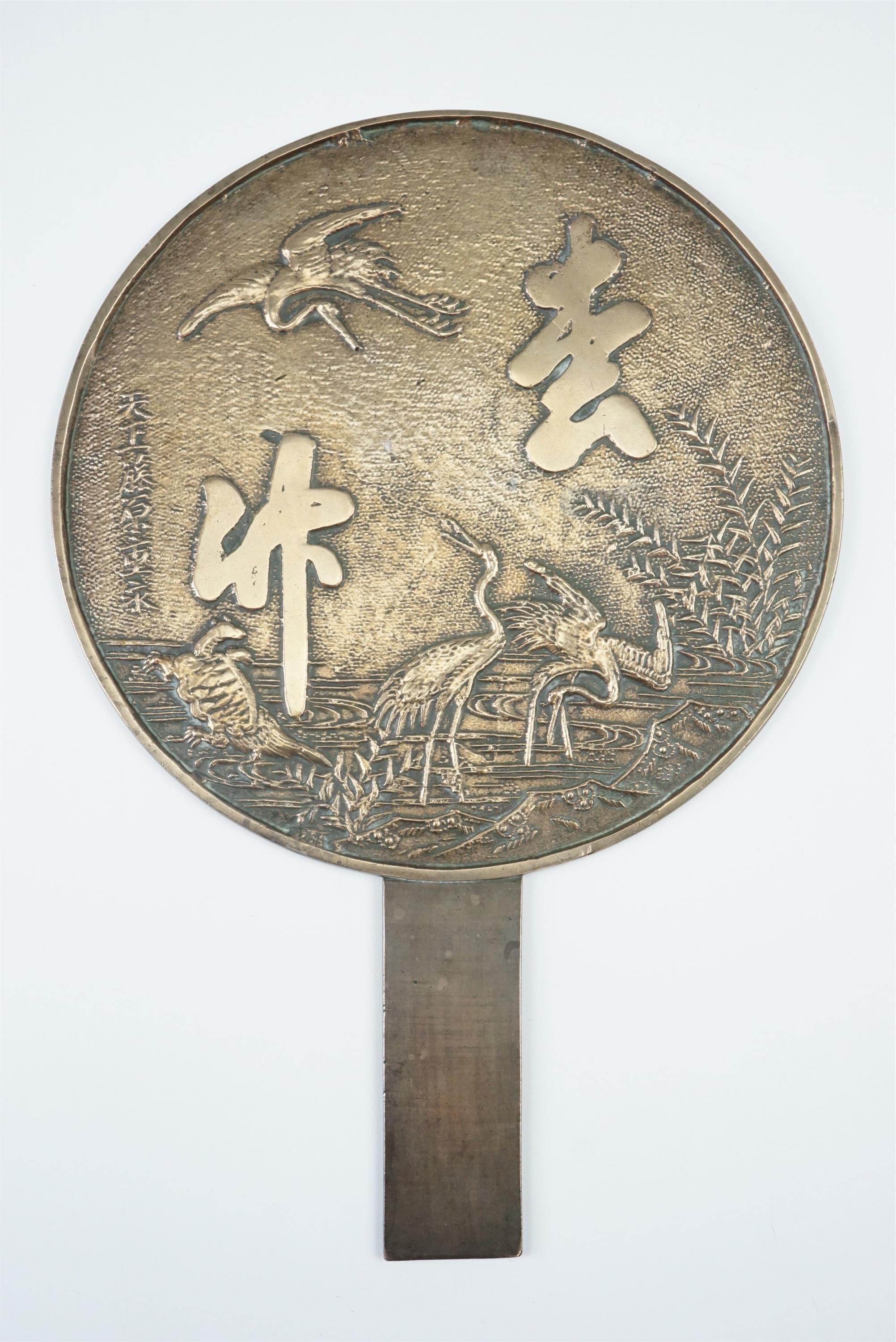 A Chinese polished bronze hand mirror, decorated with crane among bamboo and script, 20 x 29 cm