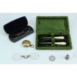 A brass sovereign case with a 1911 1 frank coin, two pairs of vintage spectacles, cased picks, and a
