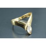 A 14 carat gold chevron solitaire ring, the flat shoulders curving to form a point, accentuated by a