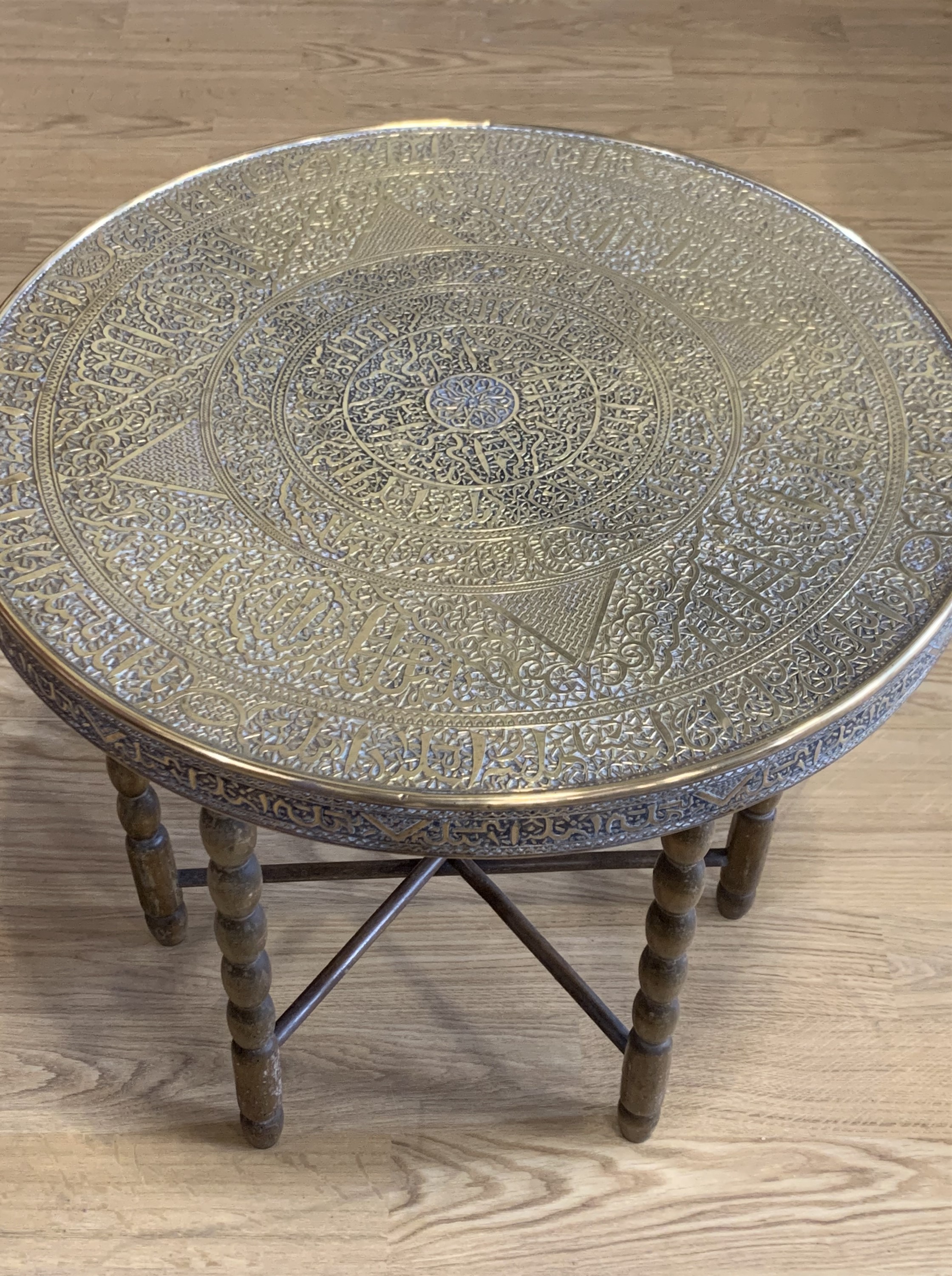 A Middle Eastern brass topped table with folding legs, 60 cm