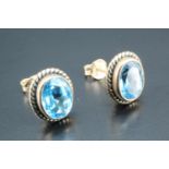 A pair of blue topaz stud earrings, the oval stones of approx 8 mm x 6 mm bezel-set and cable-framed