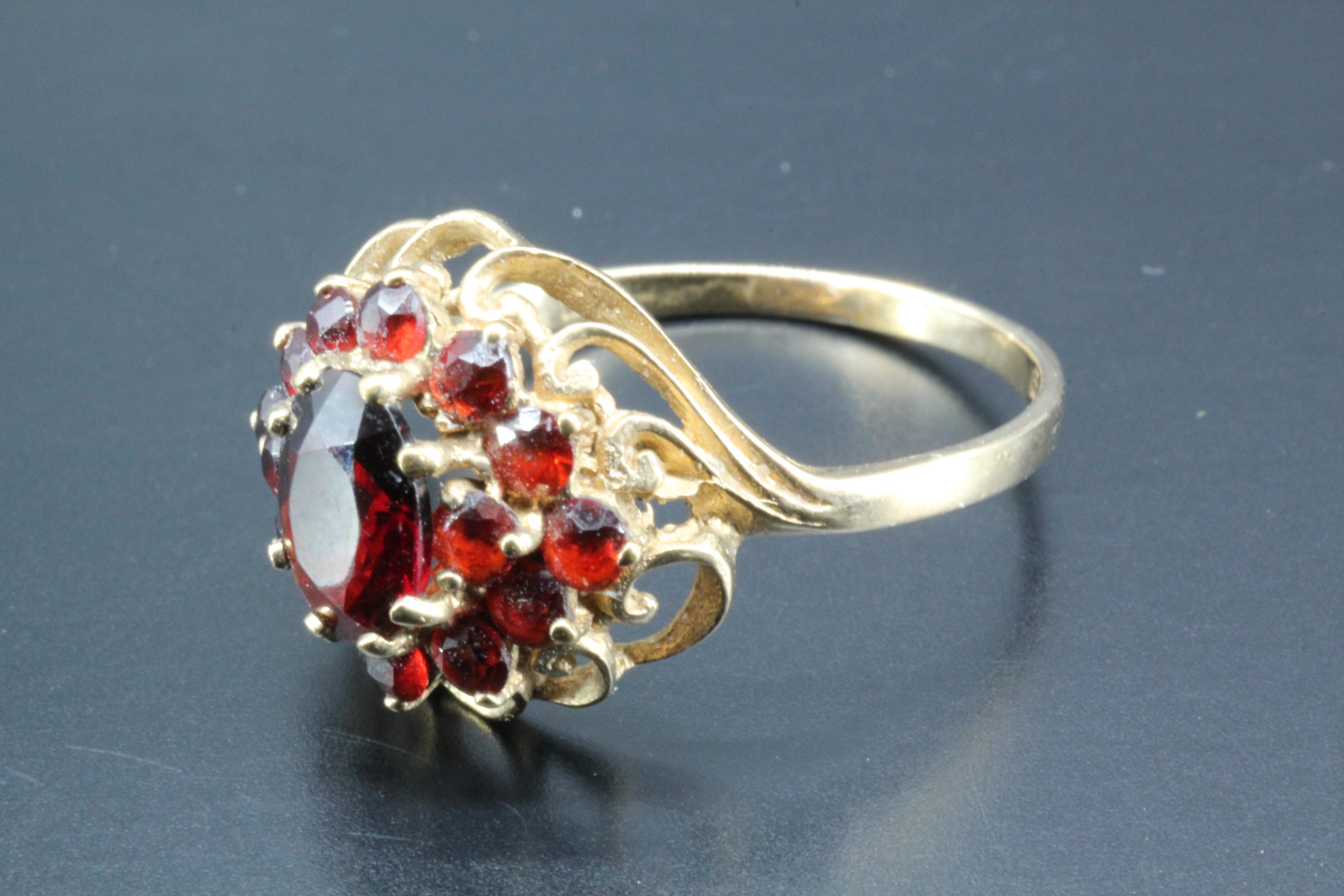 A garnet and 9 ct gold cluster ring, comprising a central oval garnet (6.5 x 5 mm) transverse set - Image 2 of 2