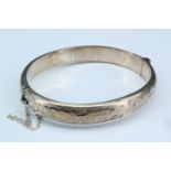 A late 20th Century silver bangle, of convex form with bright cut engraving, in a presentation