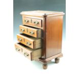 An oak diminutive chest of drawers with brass bale handles