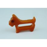 A 1930s Art Deco influenced amber composition napkin ring in the form of a dog
