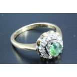 A target set tsavorite, diamond and 18 carat gold ring, having a 4mm round green garnet (0.3 ct)