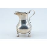 A George III influenced Edwardian silver cream jug, of baluster form raised on three trefoil feet